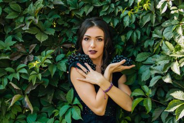 Siyah üzüm ile siyah elbiseli genç seksi esmer portresi. Kopya alanı.