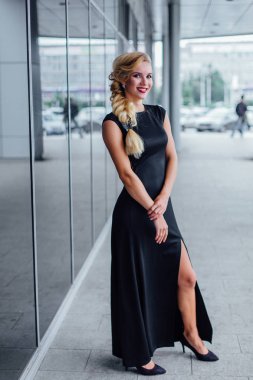 Uzun Abiye blong saçlı çekici Bayan ayna windows ile bina yanında duruyor