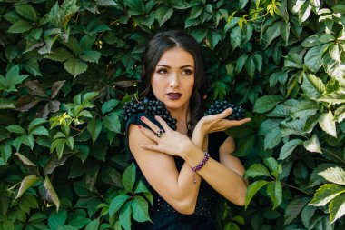 Genç seksi esmer siyah üzüm ile portresi. Kopya alanı.