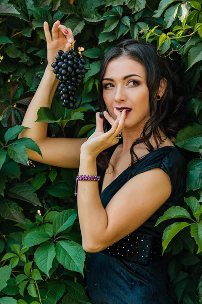 Portret van jonge sexy brunette met zwarte druiven. — Stockfoto