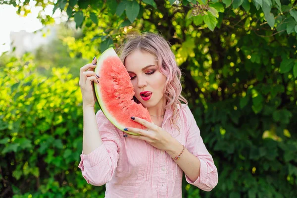 Beautiful young woman with pink hair enjoying watermelon — Stock Photo, Image