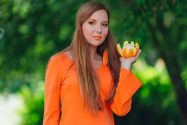 Retrato de mulher de cabelo ruivo bonita com laranja deliciosa suculenta no parque verde de verão . — Fotografia de Stock