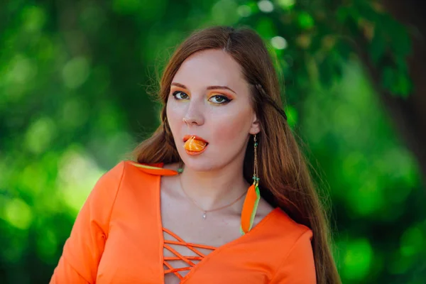 Portrait of pretty red hair woman with juicy delicious orange at summer green park. — Stock Photo, Image