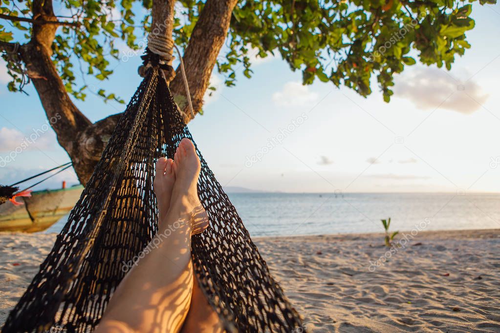 Feet of a young woman in hammock on the beach