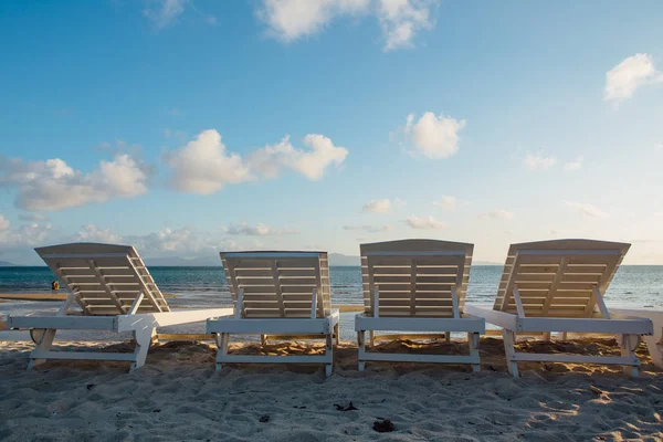 Quattro lettini bianchi in legno sulla spiaggia di sabbia — Foto Stock