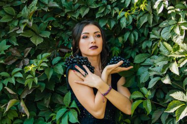 Genç seksi esmer siyah üzüm ile portresi. Kopya alanı.