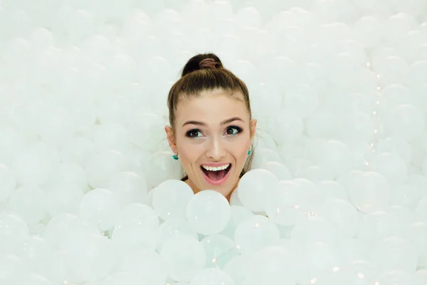 Feliz hermosa mujer pone rodeado de bolas de plástico blanco — Foto de Stock