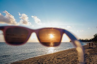 Günbatımı güneş gözlüğü ile denizde
