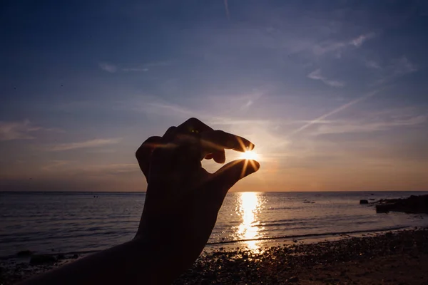 Vingers van de vrouw het vangen van de zon op zonsondergang. — Stockfoto