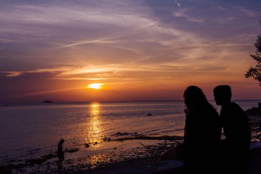 Sihouette bir kadın ve erkek ve şaşırtıcı bulutlu gün batımı
