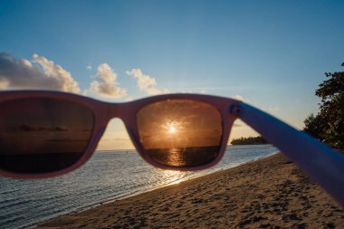 Günbatımı güneş gözlüğü ile denizde