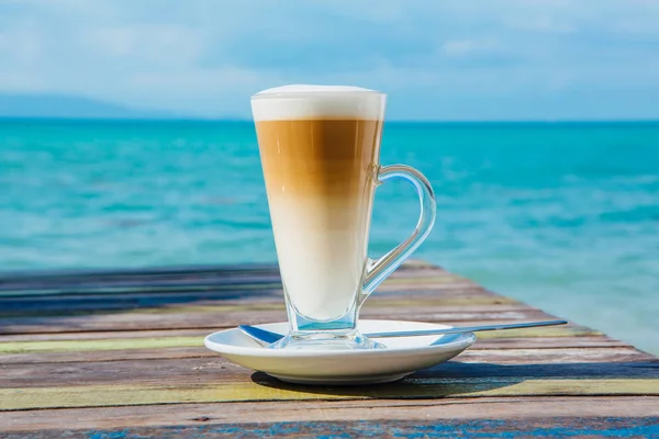Koffie latte op houten tafel met zee achtergrond — Stockfoto