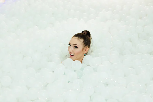 Feliz hermosa mujer pone rodeado de bolas de plástico blanco — Foto de Stock