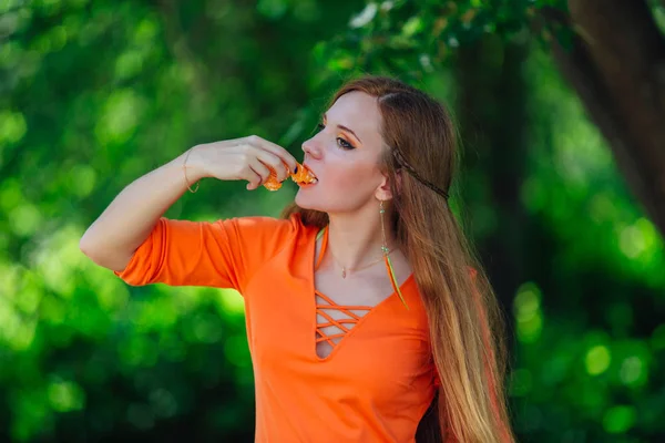 Retrato de bonita mujer pelirroja con jugosa naranja deliciosa en el parque verde de verano . —  Fotos de Stock