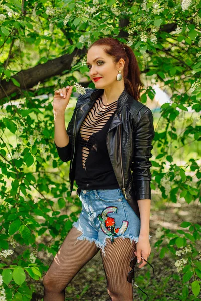 Mujer encantadora vestida con una chaqueta de cuero con flor de árbol de cerezo pájaro — Foto de Stock