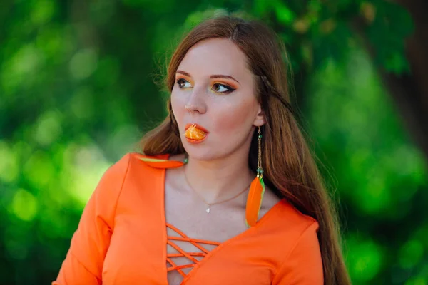 Ritratto di bella donna dai capelli rossi con succosa deliziosa arancia al parco verde estivo . — Foto Stock
