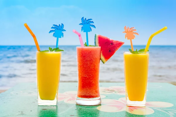 Two mango shake glasses and watermelon shake on the tropical beach