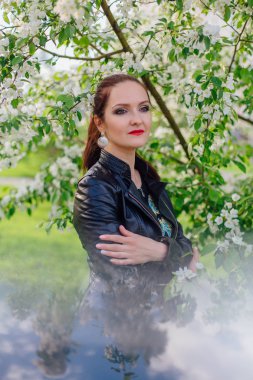 Elma ağacının altında deri ceket giymiş büyüleyici kadın