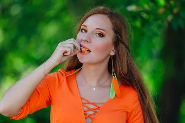 Portret van vrij rood haar vrouw met sappige heerlijke oranje in zomer groen park. — Stockfoto