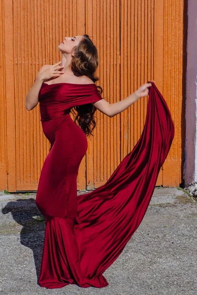 Όμορφη νεαρή γυναίκα με ένα μακρύ κόκκινο φόρεμα βράδυ με ένα τρένο — Φωτογραφία Αρχείου