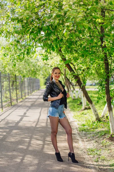 Charmante vrouw gekleed in een lederen jas staande op de weg — Stockfoto