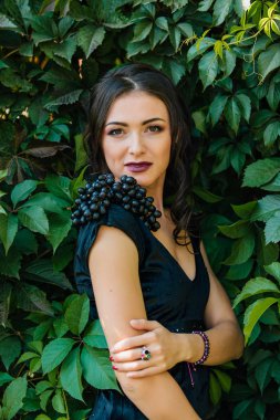 Siyah üzüm ile siyah elbiseli genç seksi esmer portresi. .