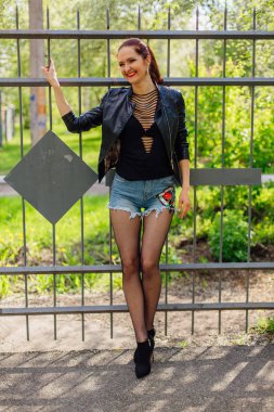 Eski bir metal çit yanında bir deri ceket durduğunu kadında