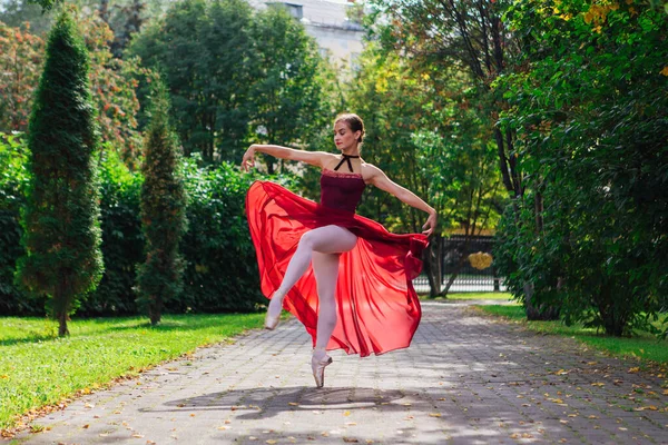 秋季公园里穿着红色芭蕾舞裙穿着尖鞋跳舞的女芭蕾舞演员. — 图库照片