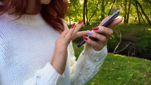 De cerca las manos de la atractiva mujer sonriente usando el teléfono inteligente charlando con amigos . — Vídeos de Stock