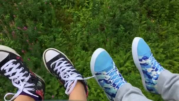 Две пары ног в кроссовках движутся на горном подъемнике в летнее время — стоковое видео
