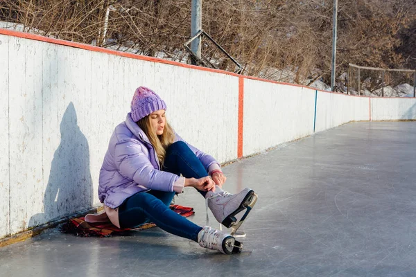 Belle jeune femme assise sur un anneau de glace et attachant lacets — Photo