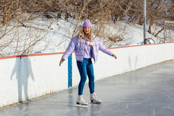 Lovely young woman riding ice skates on the ice rink. — ストック写真