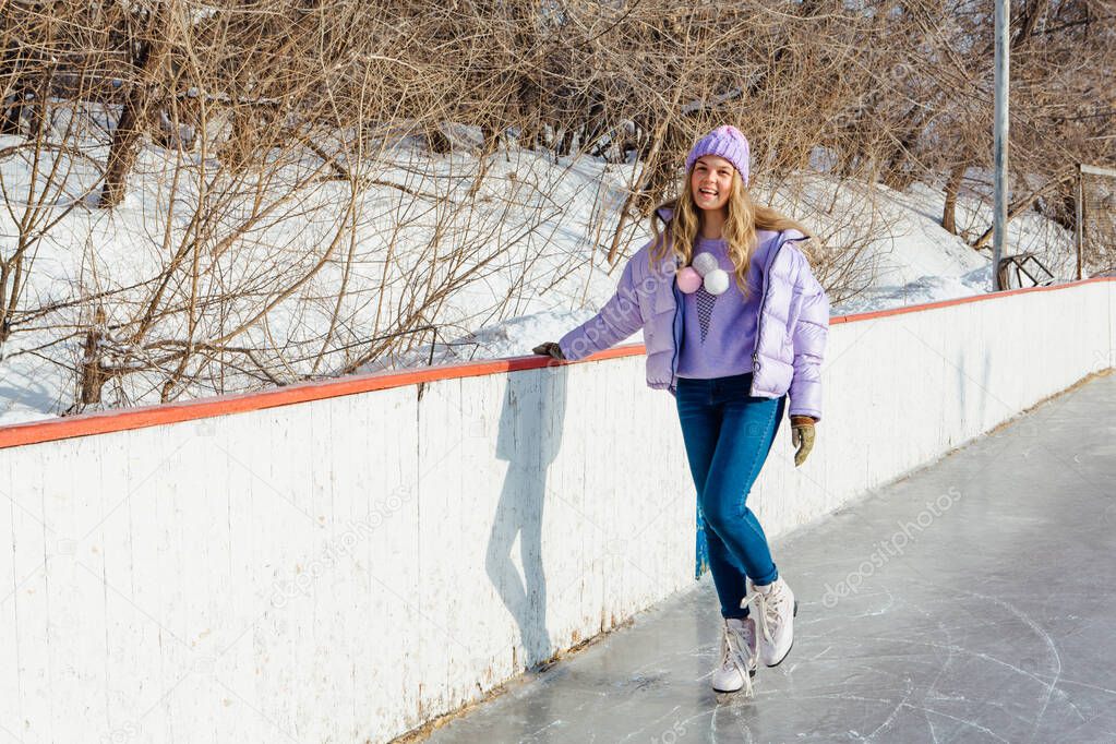 Lovely young woman riding ice skates on the ice rink.