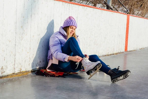 Belle jeune femme assise sur un anneau de glace et attachant lacets — Photo