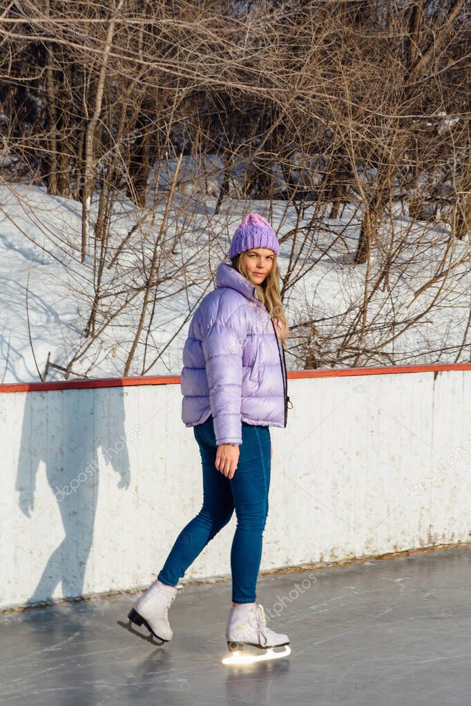 Lovely young woman riding ice skates on the ice rink.