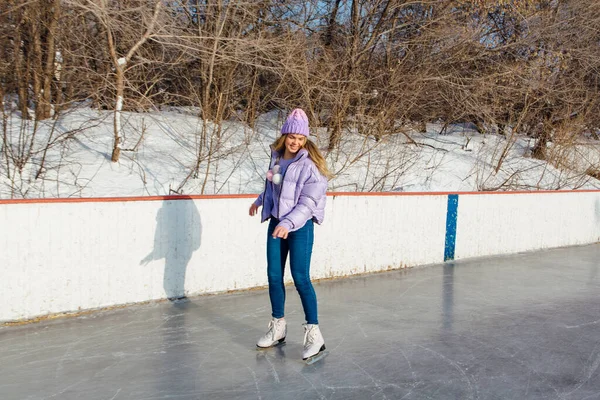 Lovely young woman riding ice skates on the ice rink. — ストック写真