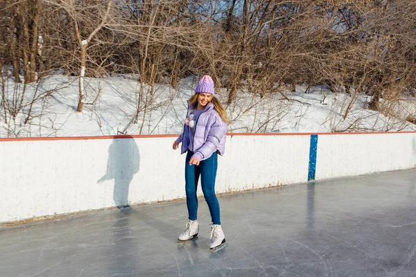 Lovely young woman riding ice skates on the ice rink.