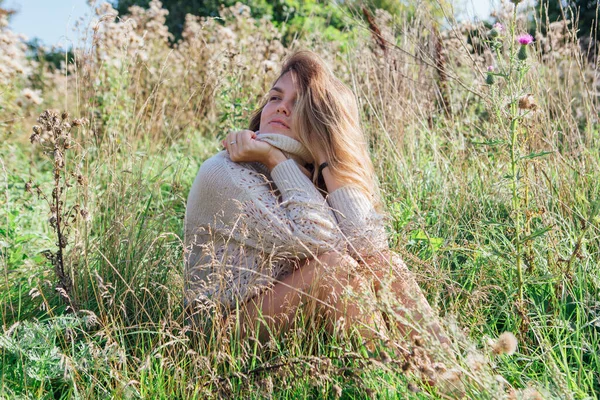 Feliz joven hermosa mujer en suéter y calzoncillos sentado con pie desnudo en un campo de agrimonia seca — Foto de Stock