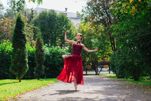 Kvinna ballerina i röd balett klänning dans i pointe skor i höstparken. — Stockfoto