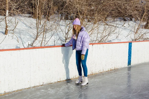 Lovely young woman riding ice skates on the ice rink.