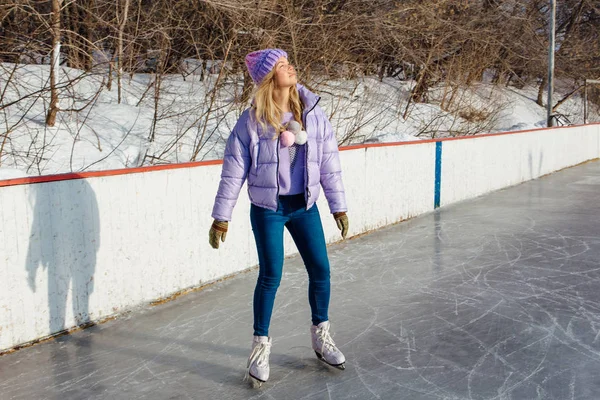 Lovely young woman riding ice skates on the ice rink. — ストック写真