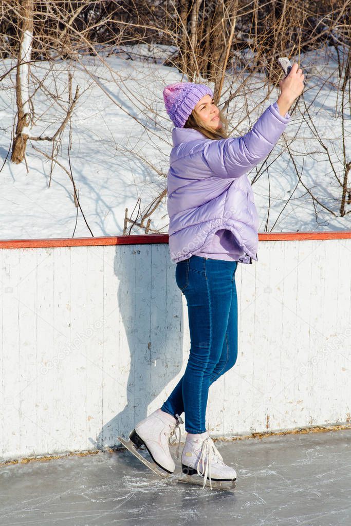 Lovely young woman riding ice skates on the ice rink.