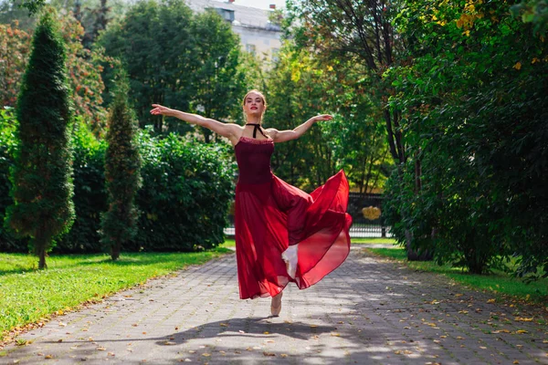 Kvinna ballerina i röd balett klänning dans i pointe skor i höstparken. — Stockfoto