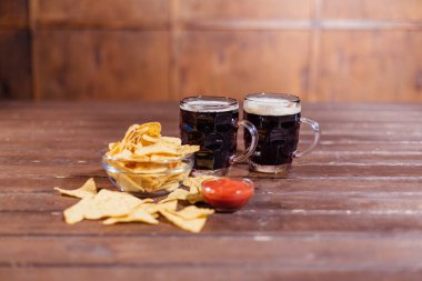 İki bardak bira ve ahşap masada atıştırmalıklar.