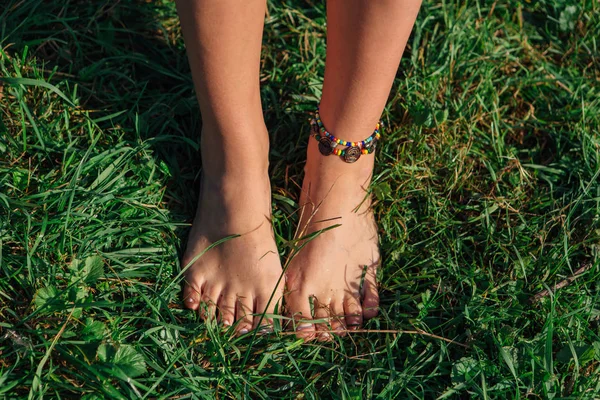 Голые женские ноги с браслетом на траве — стоковое фото