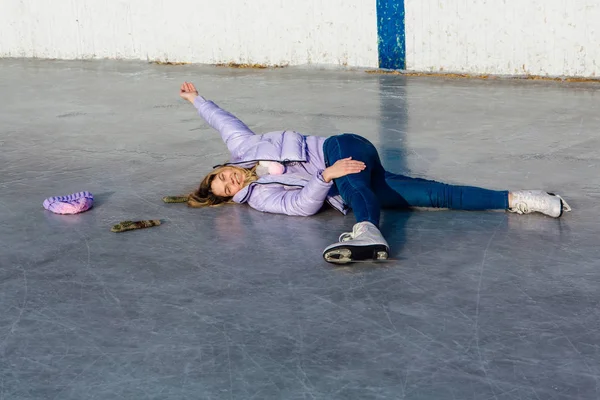 Belle jeune femme allongée sur la patinoire avec des patins à glace sur les pieds . — Photo
