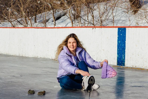 Belle jeune femme assise sur un anneau de glace et attachant lacets — Photo