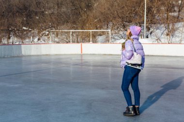 Buz patenleriyle buz pistinde sallanan genç ve güzel bir kadın..