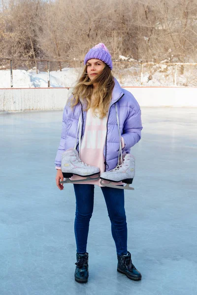 Preciosa joven con patines de hielo colgando del cuello en la pista de hielo . — Foto de Stock