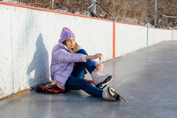 Belle jeune femme assise sur un anneau de glace et attachant lacets — Photo